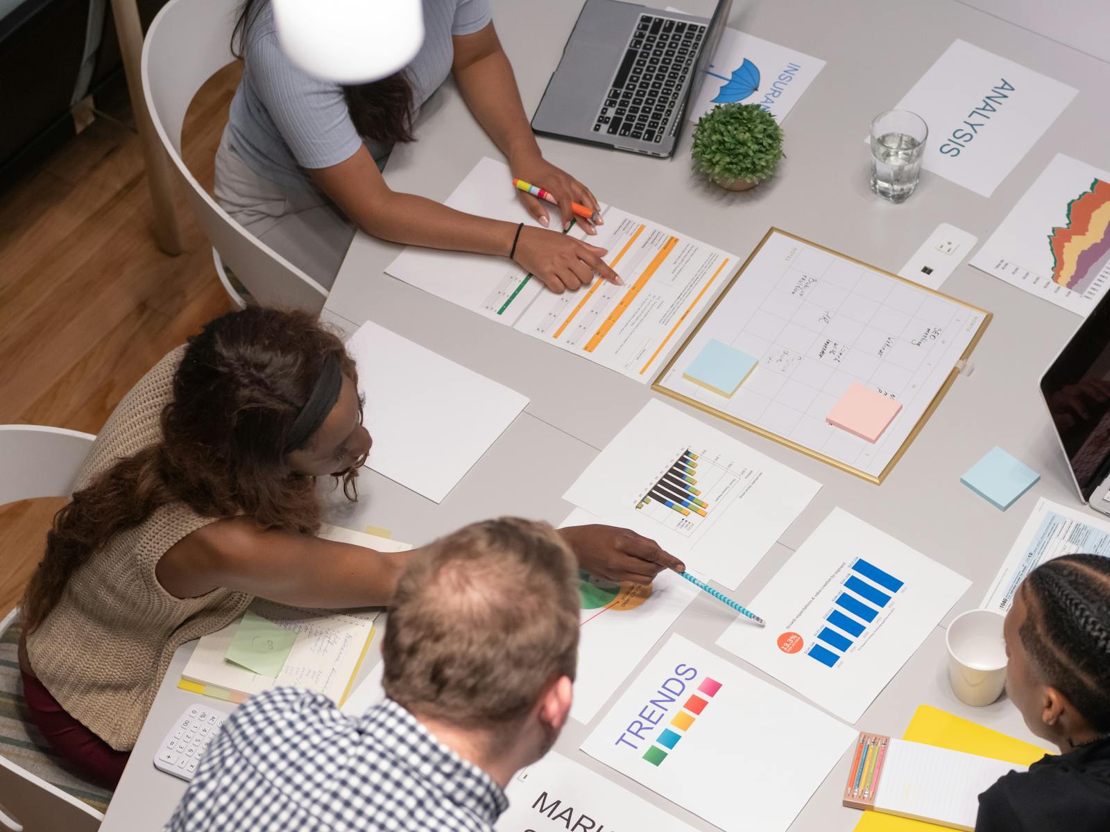 Groupe de personnes travaillant sur une table de réunions sur laquelle sont posées des feuillles papiers avec des graphiques